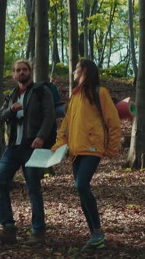 Young Caucasian Travelers Walk Through the Green Forest Laugh Talk to Each Other Enjoying the Life