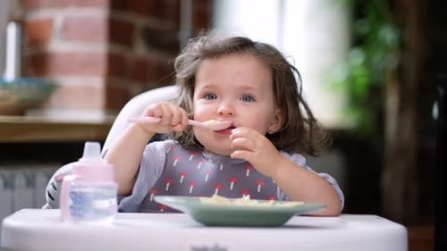 Toddler Eating Pasta in High Chair Close Up