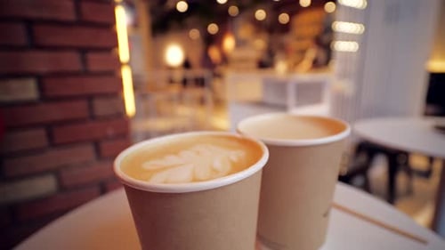 Close Up Two Cardboard Coffee Cups Take Away on Table Over Bokeh Background Coffee Shop and Take