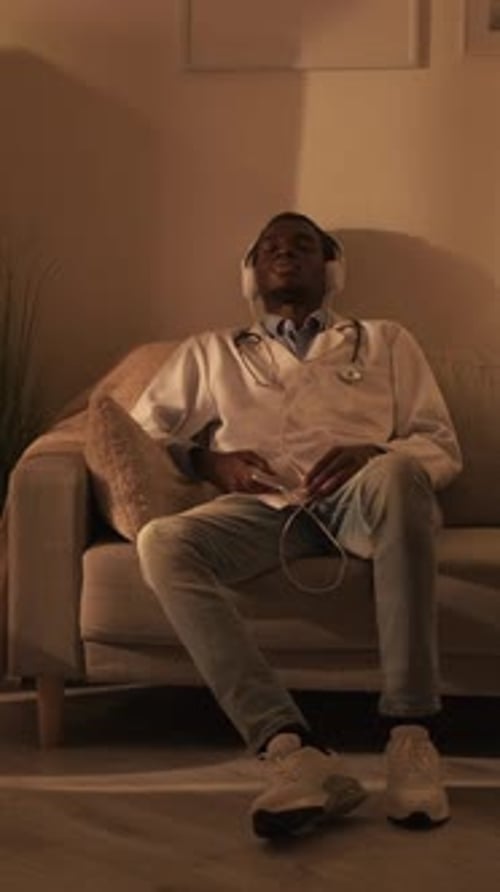 Doctor Relaxing with Headphones on Couch at Home