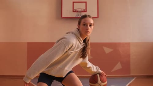 Young Female Basketball Player Dribbling in a Gym