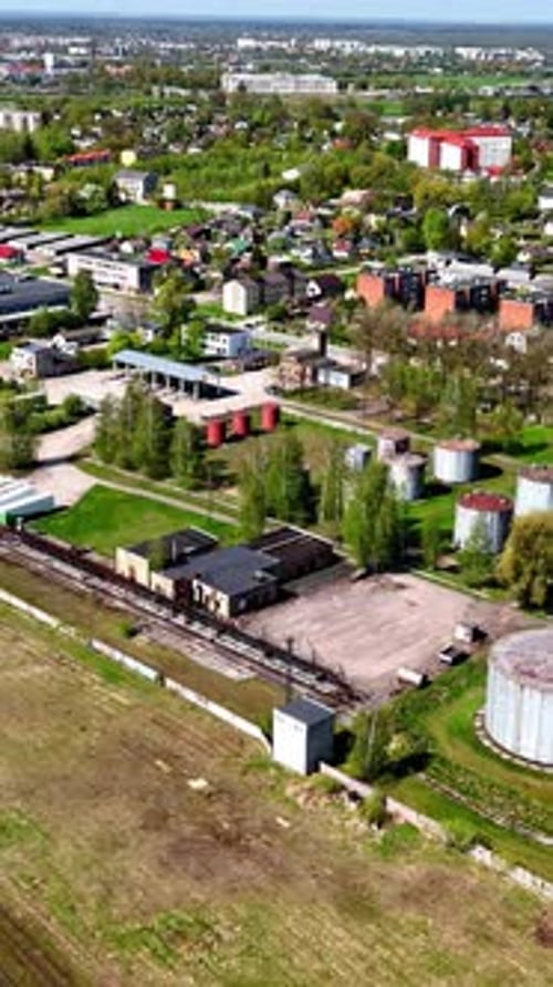 Aerial of suburban neighborhood next to industrial trash facility, vertical view
