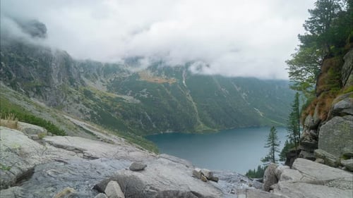 mountain lake against the backdrop of high mountains and fast-moving clouds, time-lapse sun glare