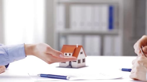 Businessman giving house keys to woman real estate deal in modern office