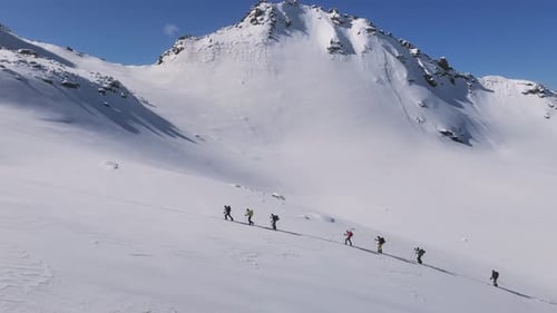 Gruppe von Alpinisten, die einen verschneiten Berghang erklimmen. Aus der Luft