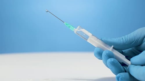 Surgical assistant prepares injection needle, push air out of plastic syringe