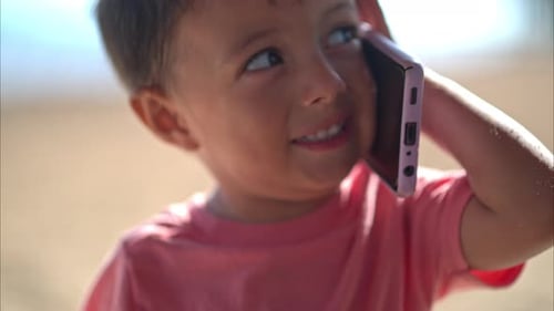 Young Boy Talking on Cell Phone at Beach