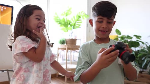 Siblings' Joy: Sharing a Camera for a Fun Snapshot