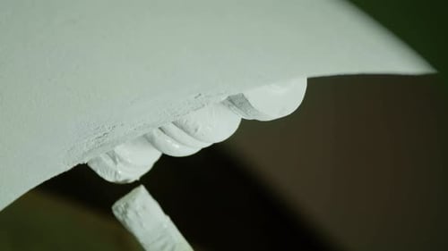 Extreme Close-up of Worker Hand Painting Ornate Plaster Detail