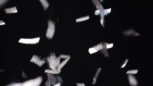 Silver Confetti Falling Against Black Background