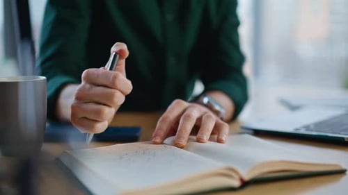 Cuaderno de escritura a mano de gerente que crea un proyecto empresarial en el lugar de trabajo de cerca