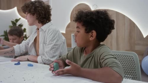 Teacher showing children how to sculpt with clay