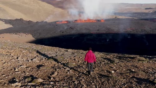 Man hiking towards new 2022 fissure volcano in Iceland on sunny day, aerial