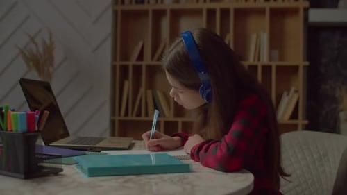 Teen Studying at Home with Laptop and Notebook
