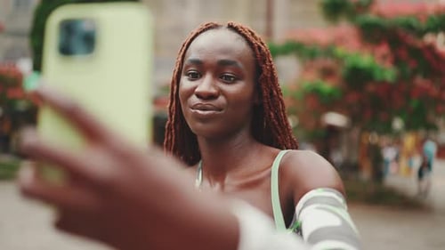Smiling gorgeous woman stands outside on the street and uses mobile phone