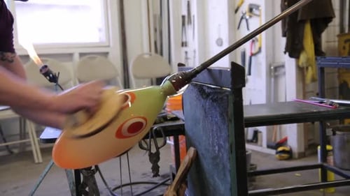 Glass Artist Shaping Molten Glass in Workshop