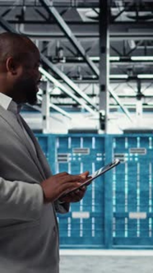 Vertical Video Cheerful Server Room Engineer Troubleshooting Backend Operations Using Tablet