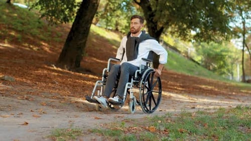 On Sunny Day Young Man Disabled in Wheelchair Rides in Park at Sunlight Paralysis Disability