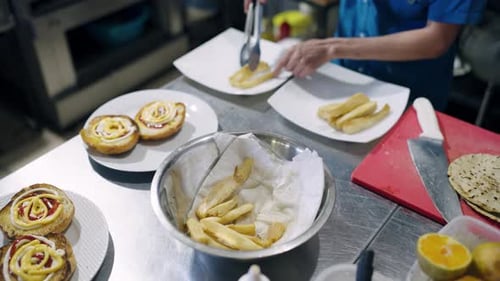 Chef Plates Golden French Fries with Sauced Burgers