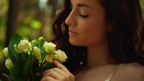 Closeup Smiling Bride Admiring Flowers in Garden. Beautiful Woman Holding White Roses