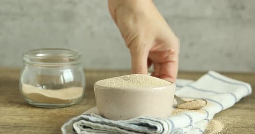 Spoon Adding Yeast to Bowl on Wooden Table