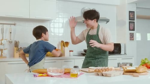 Father and Son Joyfully Cook Together in Kitchen