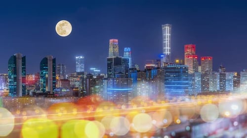 The moon rises in the city sky at night,The moon slowly rises over the city at night