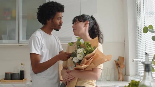 Affectionate Couple Giving Flowers in Bright Kitchen