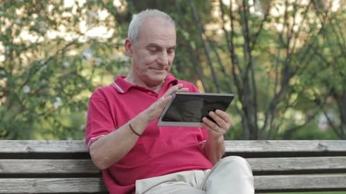 Senior man using tablet computer in the park
