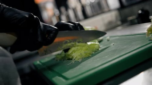 The chef cuts vegetables (cabbage) on a cutting board in restaurant in a professional kitchen