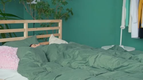 A Happy Young Woman Wakes Up in a Happy Mood Stretching Cheerfully in Bed