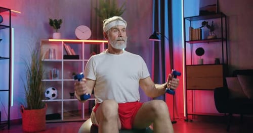 Senior Man Doing Arm Curls on Exercise Ball