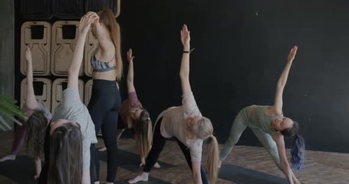 Women Practicing Yoga Triangle Pose with Instructor
