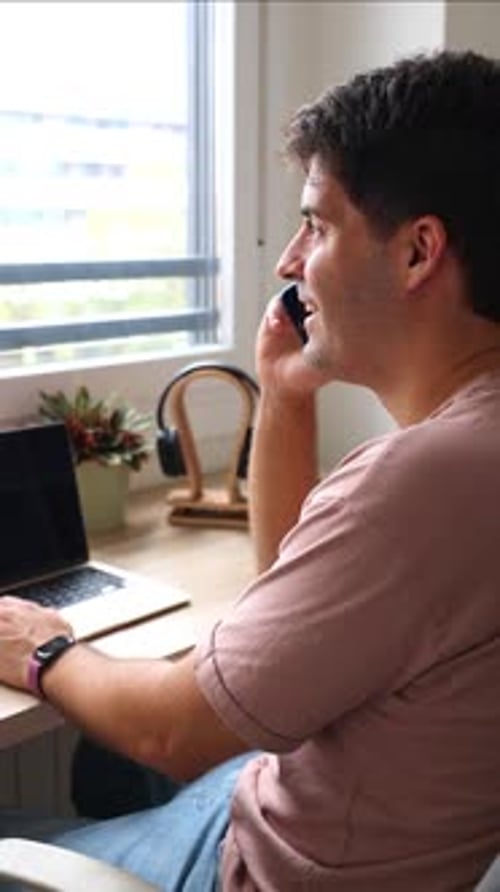 vertical Young hispanic man teleworking from home talking on the phone