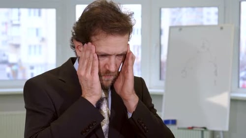 Homme d'affaires stressé souffrant de maux de tête dans un bureau moderne