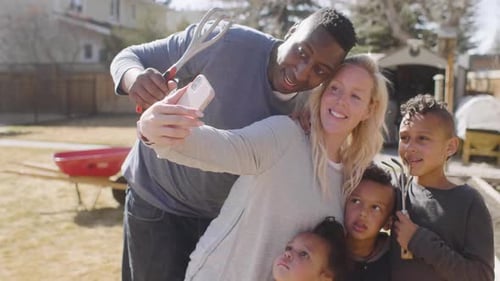 Happy Family Taking Selfie Outdoors With Gardening Tools