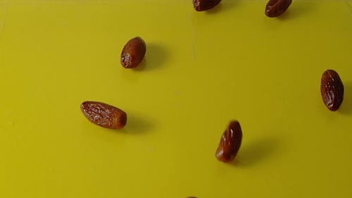 Dates Falling on Bright Yellow Surface, Close Up
