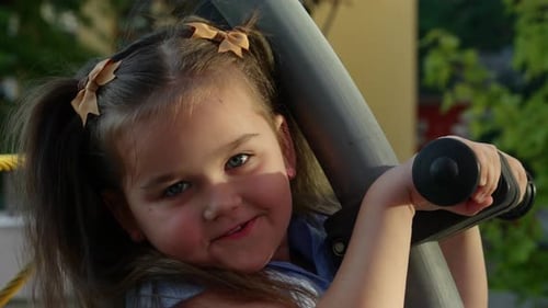 Young Girl Enjoys Playful Moments on a Playground Swing Set in the Afternoon Sun