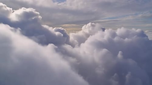 Aerial flight through white fluffy clouds above the sky at s