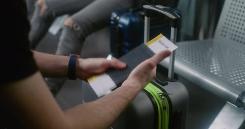 Imagem aproximada de um homem com mala sentado na sala de embarque do hub da companhia aérea esperando o voo