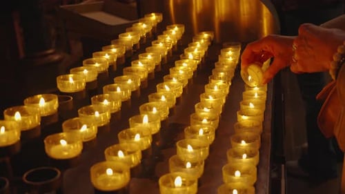 A believer lights candle on the altar. A lot of burning candles in temple. Concept of memorial day