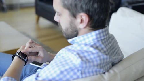 Man using smart watch and mobile phone indoors