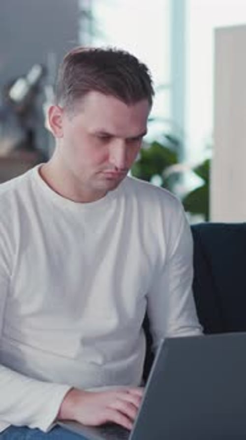 Young Attractive Entrepreneur Caucasian Man Using Laptop Looking Into Camera While Sitting in Casual