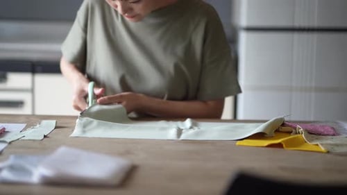 Adult Cuts Fabric on Wooden Table at Home