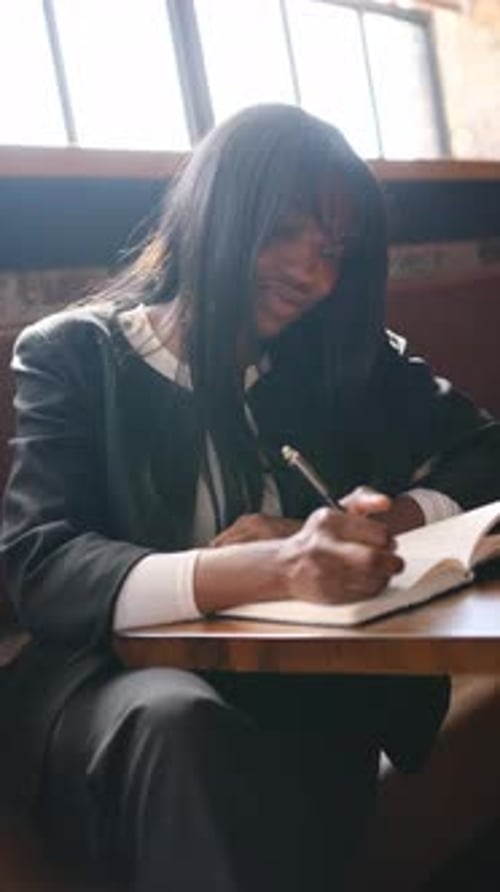 Focused Black Businesswoman Writing in Notebook