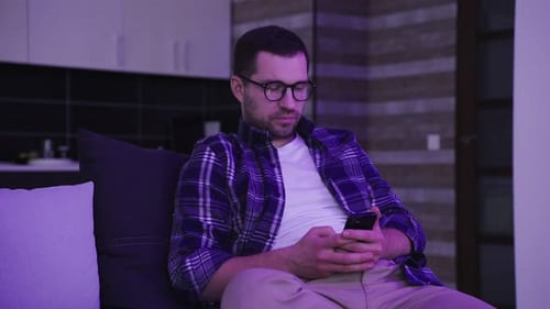 Man On Couch Using Smartphone At Home