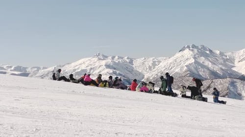 Snowboarders Resting On Snowy Mountain, Sunny Winter Day