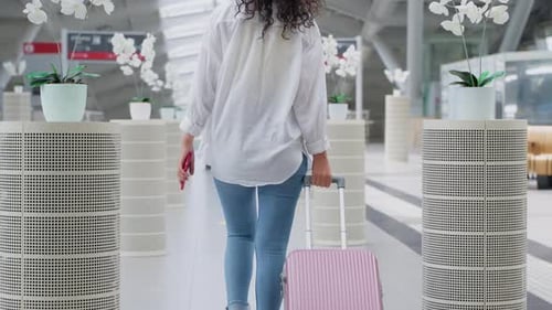 Woman with Suitcase is Walking Inside Modern Building of International Airport or Railway Terminal