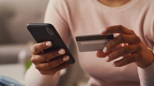 Woman Uses Phone with Credit Card at Home