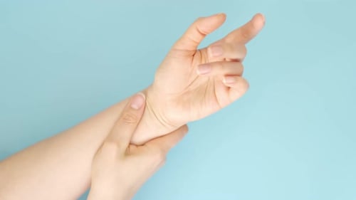 Close Up Video Unrecognizable Woman Massaging Hand Suffering From Joint Pain on a Blue Background